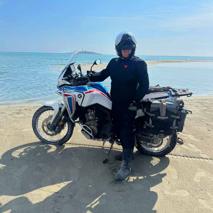 Adventure motorcyclist with a touring bike on the Caspian Sea beach in Awaza resort Turkmenistan