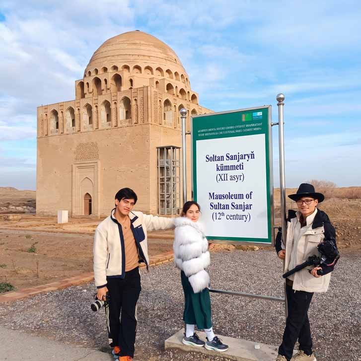 Tourists standing by the information sign at the ancient Sultan Sanjar mausoleum in Merv Turkmenistan