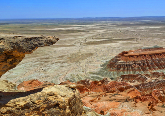 Panoramic view of the spectacular red rock formations at Yangikala Canyon, a highlight of Hazar Merjeni’s 4x4 off-road adventure tours in Turkmenistan.