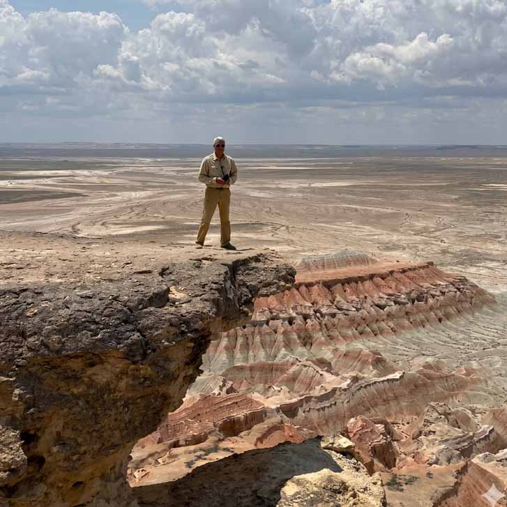 A traveler standing on the edge of the scenic Yangykala canyon under a cloudy sky in Turkmenistan